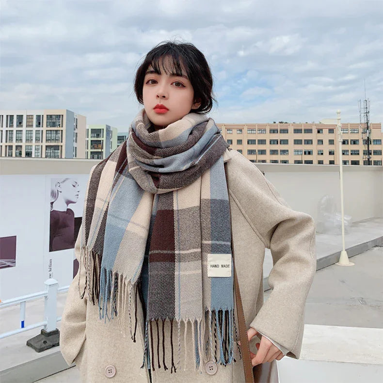 Woman wearing beige coat and blue, brown plaid handmade scarf outdoors in urban setting