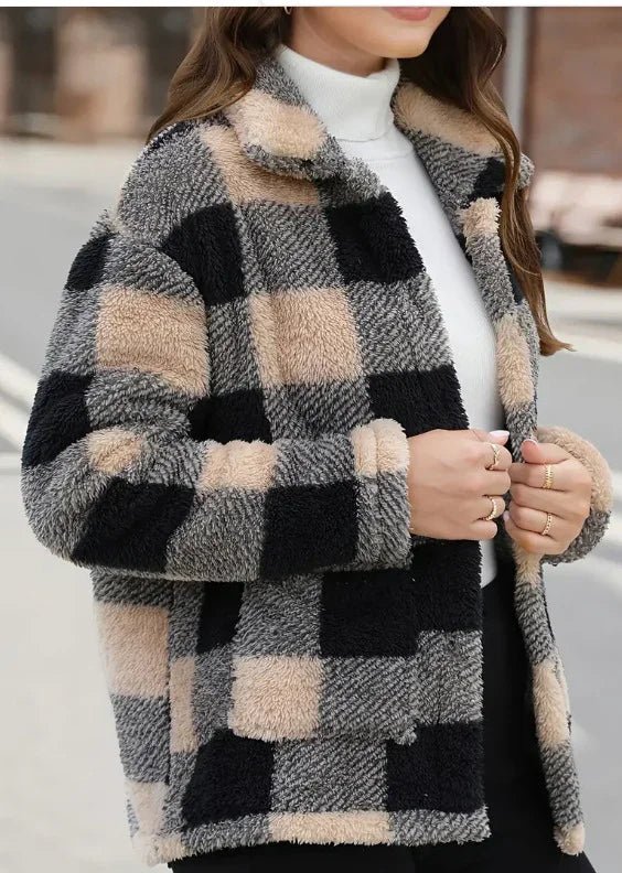 Close-up of a woman wearing a cozy beige, black, and gray plaid fleece jacket over a white turtleneck
