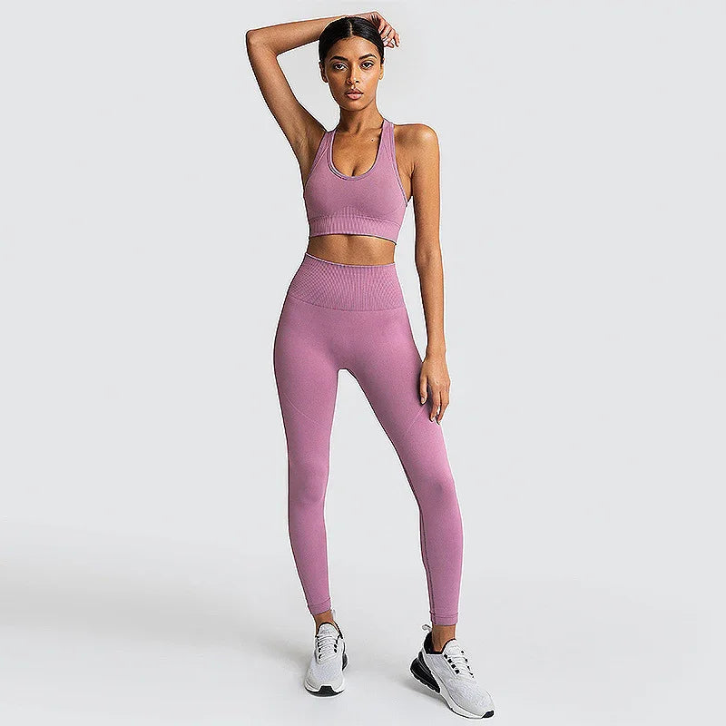 Woman in pink seamless sports bra and leggings set, posing in athletic wear on plain background