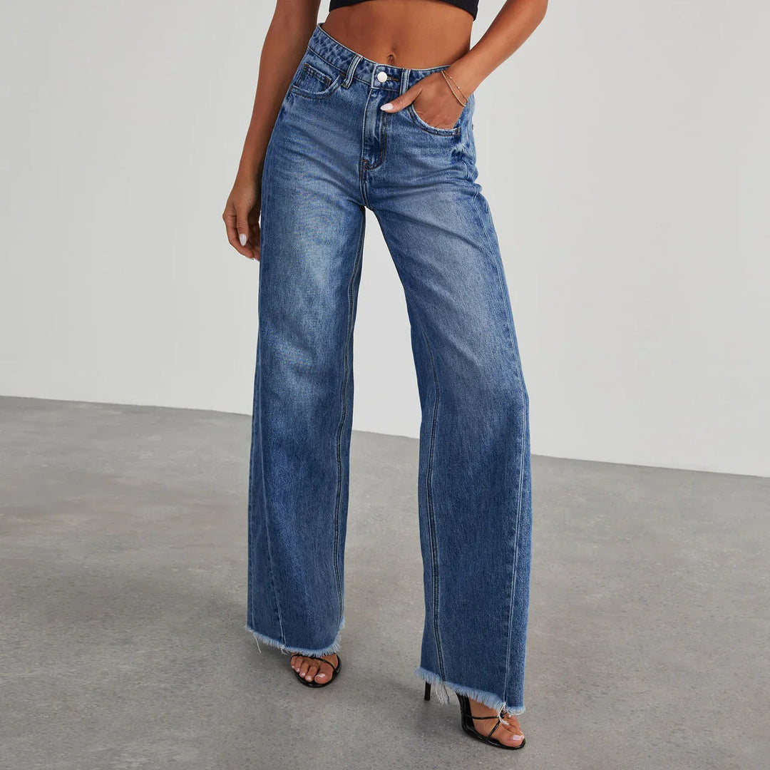 Woman wearing blue high-waist wide-leg jeans with raw hem and black strappy heeled sandals