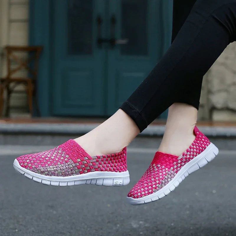 Women's casual slip-on woven pink and gray sneakers with white soles, worn with black leggings