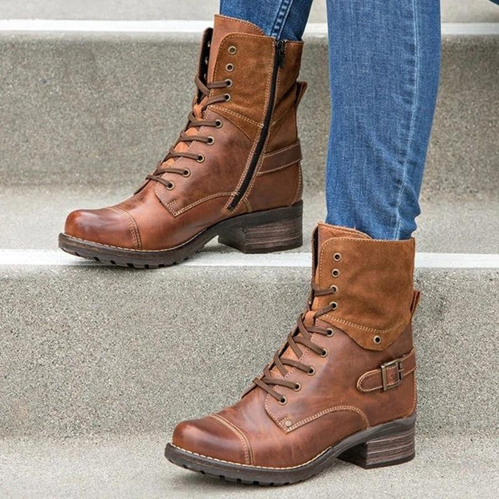 Brown leather lace-up ankle boots with side zipper and buckle worn with blue jeans on concrete steps