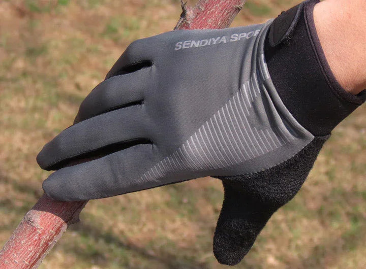 Close-up of a hand wearing gray SENDIYA SPORT gloves gripping a tree branch outdoors