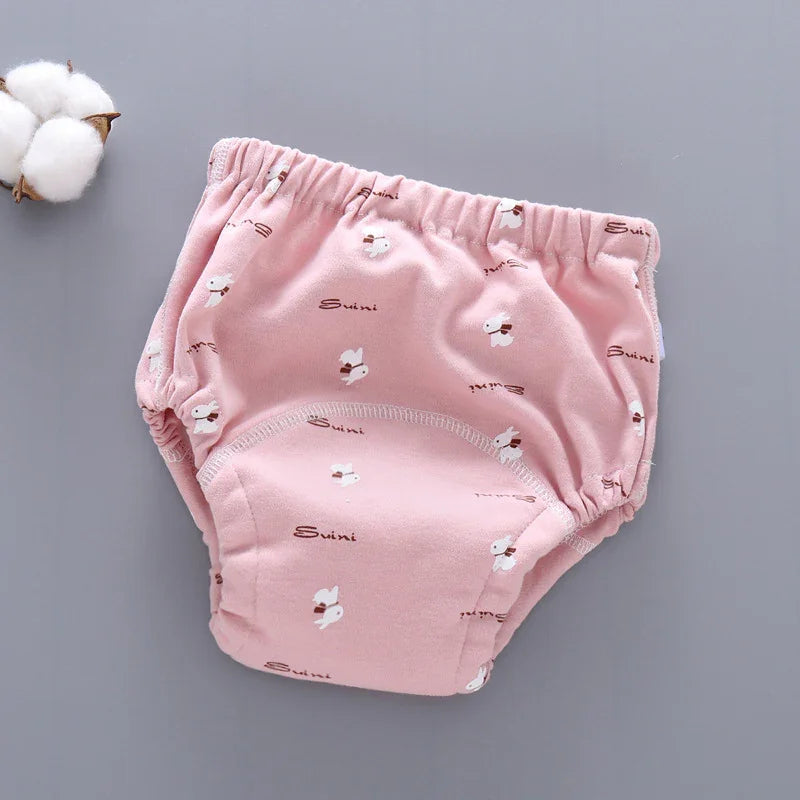 Pink baby training pants with white bunny print and elastic waist on gray background