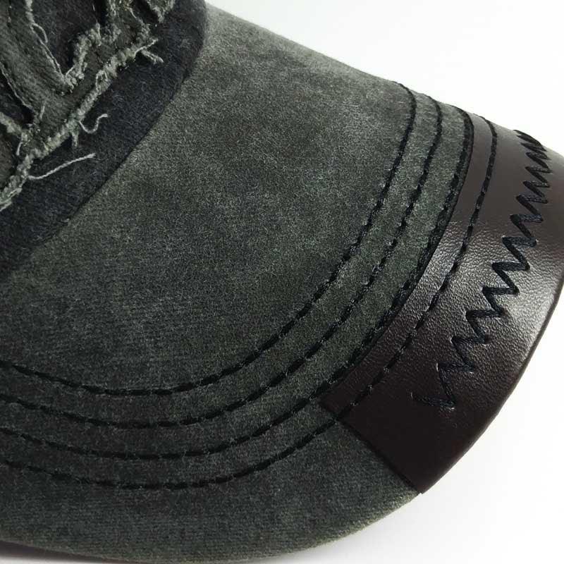 Close-up of green suede boot toe with black zigzag stitching on dark brown leather trim