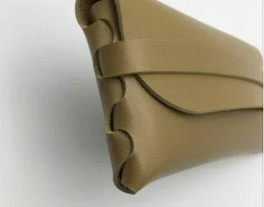 Close-up of a tan leather designer handbag corner with stitched detailing on white background