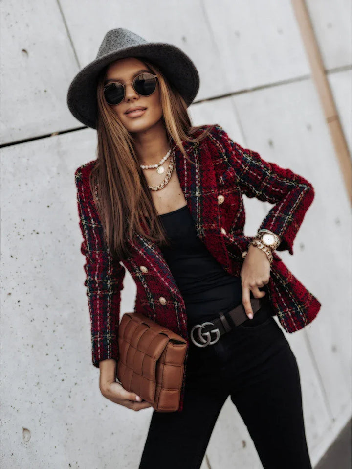 Stylish woman in gray fedora, sunglasses, red plaid blazer, black outfit, and brown quilted clutch bag