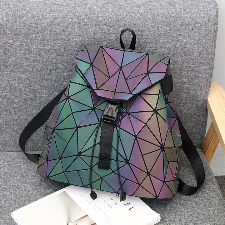 Reflective geometric backpack with black straps on gray chair next to magazines