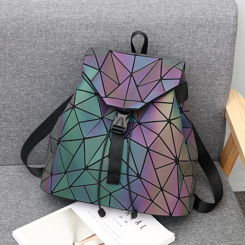 Geometric pattern reflective backpack with black straps on gray fabric chair with book