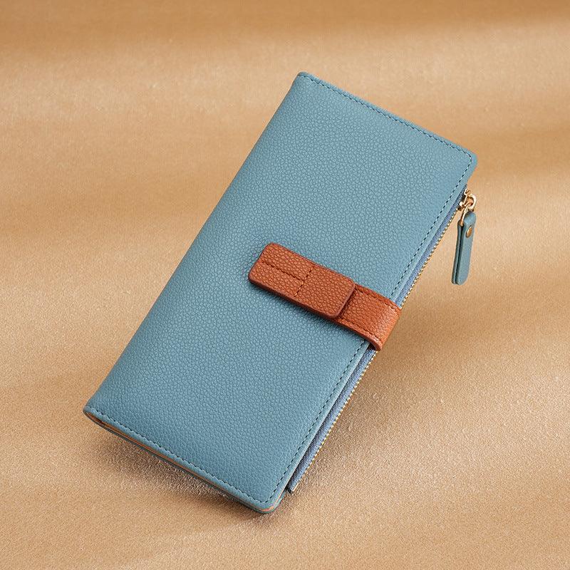 Blue textured leather wallet with brown strap and gold zipper on beige background