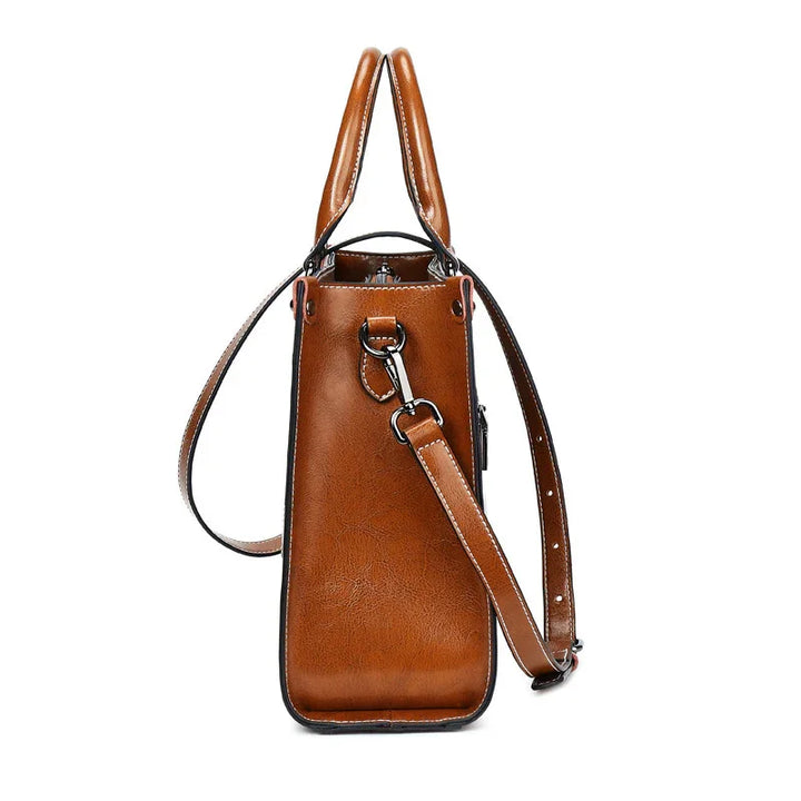 Side view of a brown leather handbag with adjustable strap and silver hardware on white background