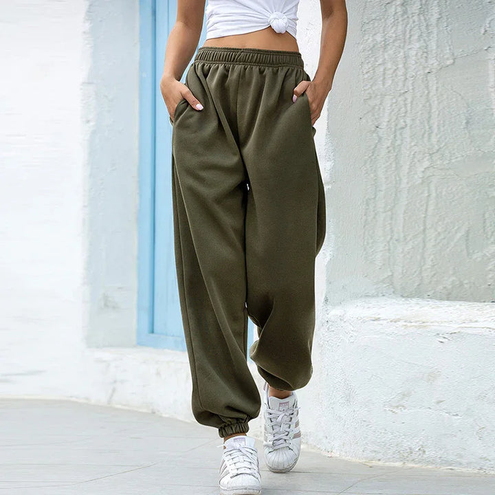 Woman wearing olive green jogger pants and white sneakers walking in urban setting