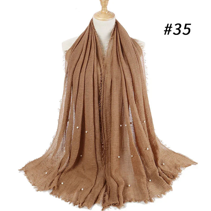 Beige lightweight scarf with fringed edges and pearl embellishments displayed on mannequin