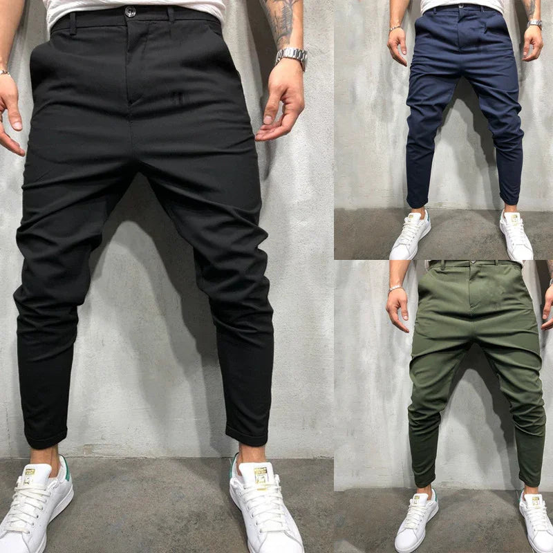 Men's slim fit casual pants in black, navy blue, and olive green worn with white sneakers
