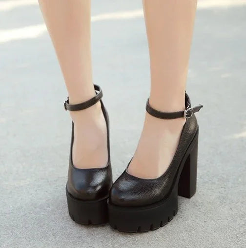 Black chunky platform heels with ankle straps on a concrete surface