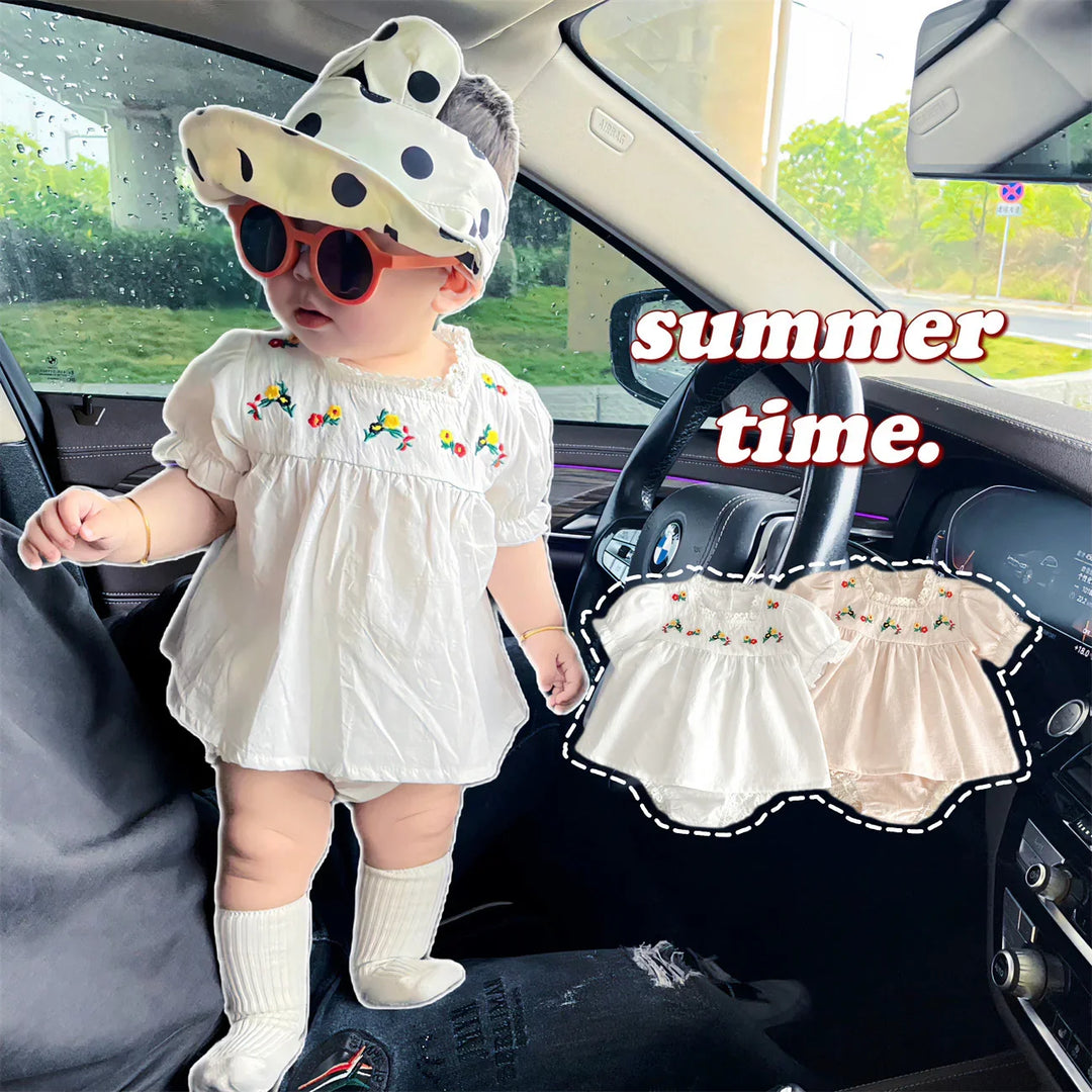 Baby in white floral dress, polka dot hat, and socks standing inside BMW car interior