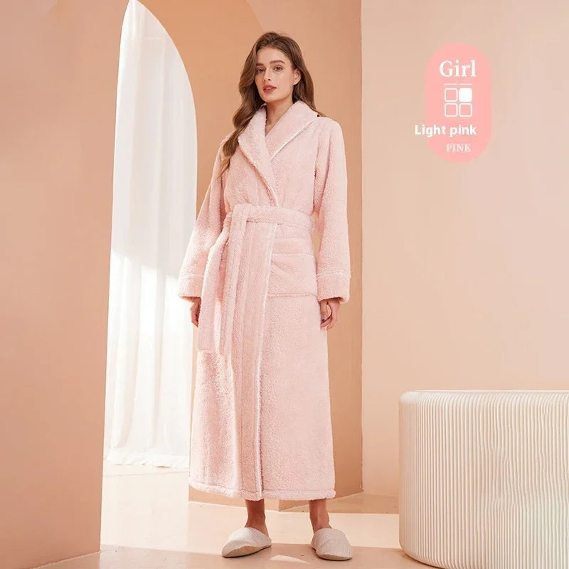 Woman wearing long light pink plush bathrobe with belt, standing indoors near arch and white curtain
