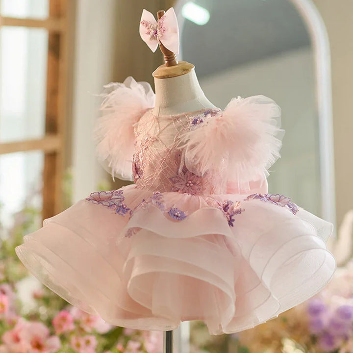 Pink baby dress with puff sleeves and floral embroidery on mannequin with matching bow