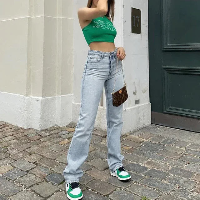 Street style fashion with a woman wearing high-waisted light blue jeans, green crop top, and green white sneakers