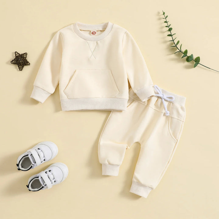 Cream toddler outfit with sweatshirt, pants, white sneakers, decorative star and green twig