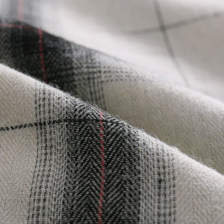 Close-up of soft woven fabric with black, white, and red plaid pattern and textured fibers
