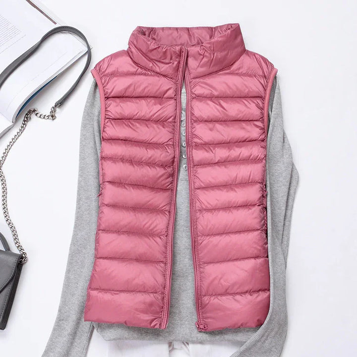Pink quilted sleeveless puffer vest on gray long-sleeve shirt with gray purse and chain strap