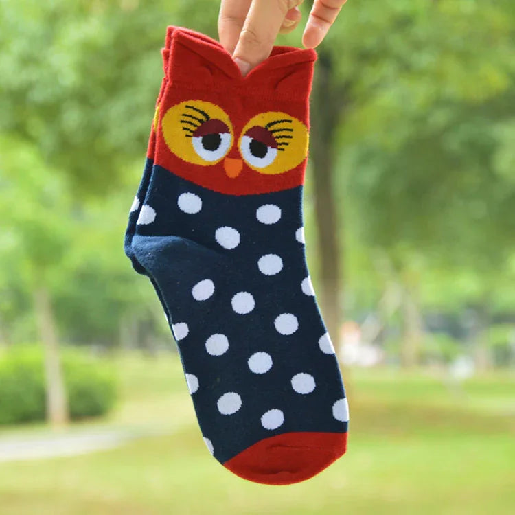 Hand holding a colorful sock with an owl face design, red top, navy with white polka dots, outdoor background