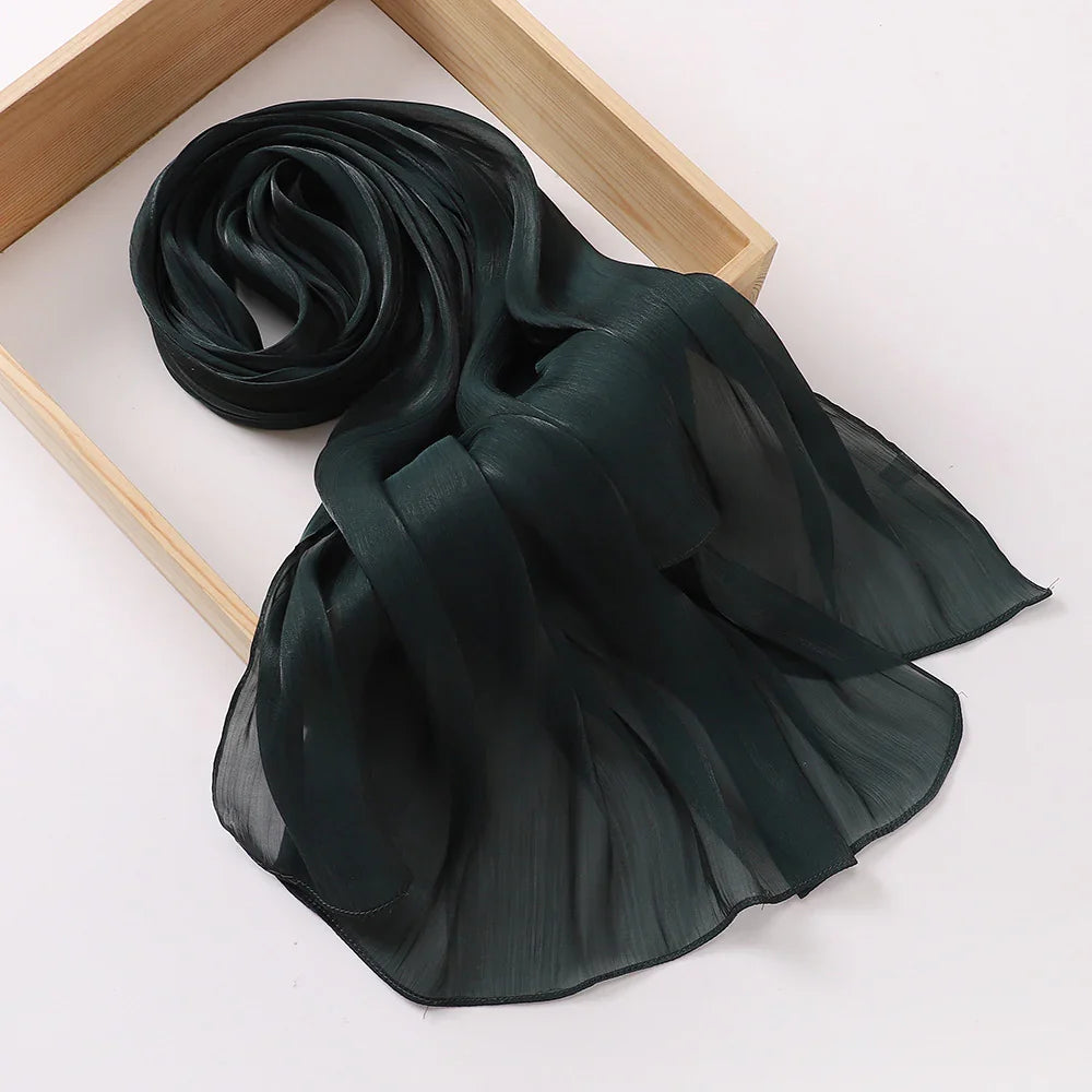 Dark green lightweight chiffon scarf displayed on light wooden frame with soft folds