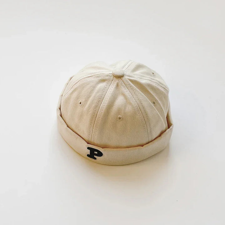 Beige cotton fisherman cap with black letter P embroidery on folded brim on white background