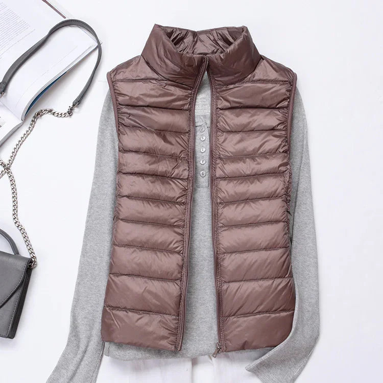 brown quilted puffer vest over gray long sleeve shirt with black handbag on white background