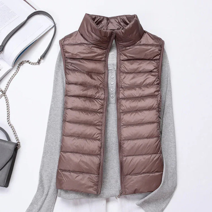 brown quilted puffer vest over gray long sleeve shirt with black handbag on white background