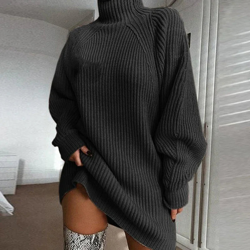 Woman wearing oversized black ribbed knit sweater dress with turtleneck and snake print boots indoors