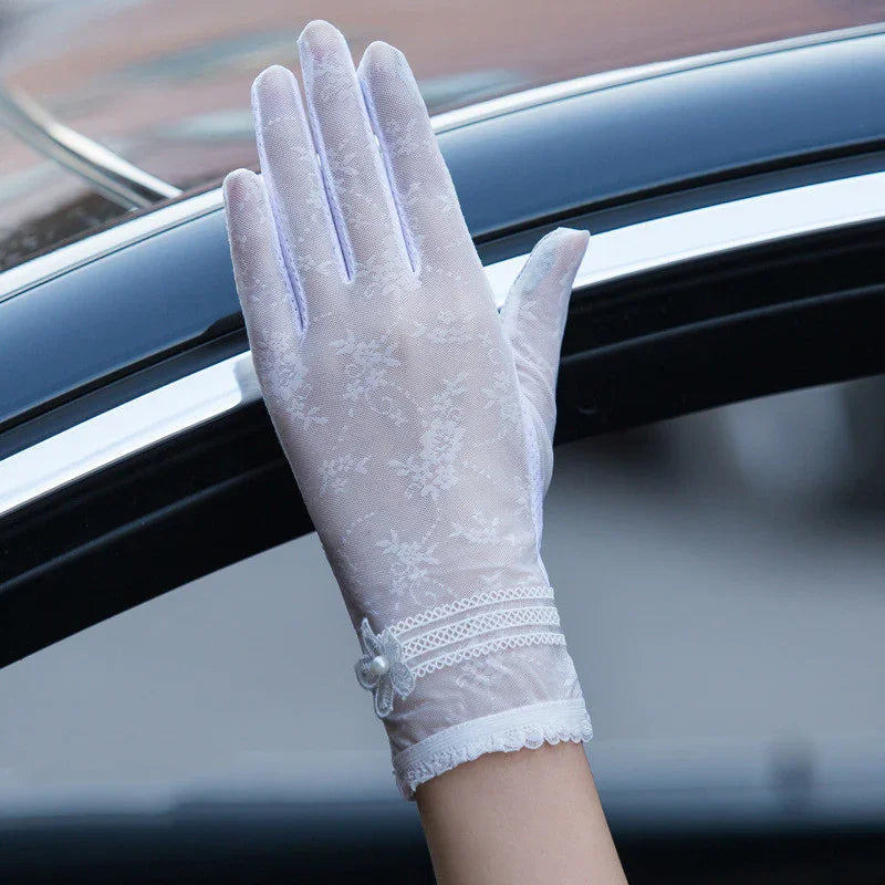 Hand wearing elegant white lace glove with floral pattern and pearl detail, raised outside car window