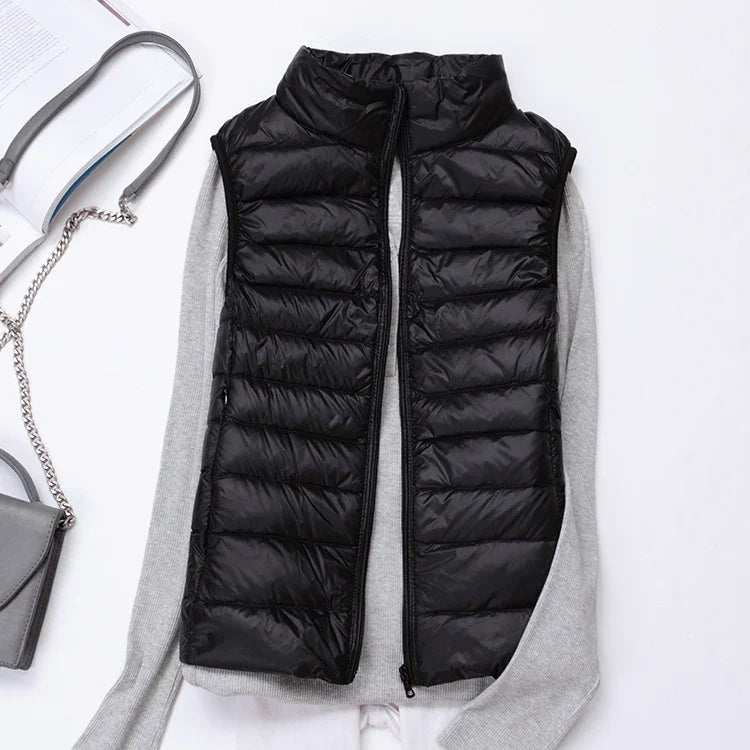Black quilted sleeveless puffer vest layered over gray long sleeve sweater with open zipper on white background