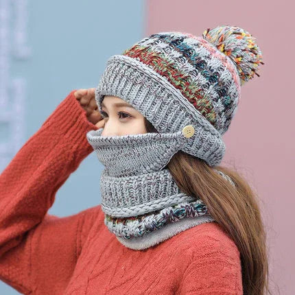 Woman wearing multicolor knitted beanie with pompom and matching grey knit face cover and scarf