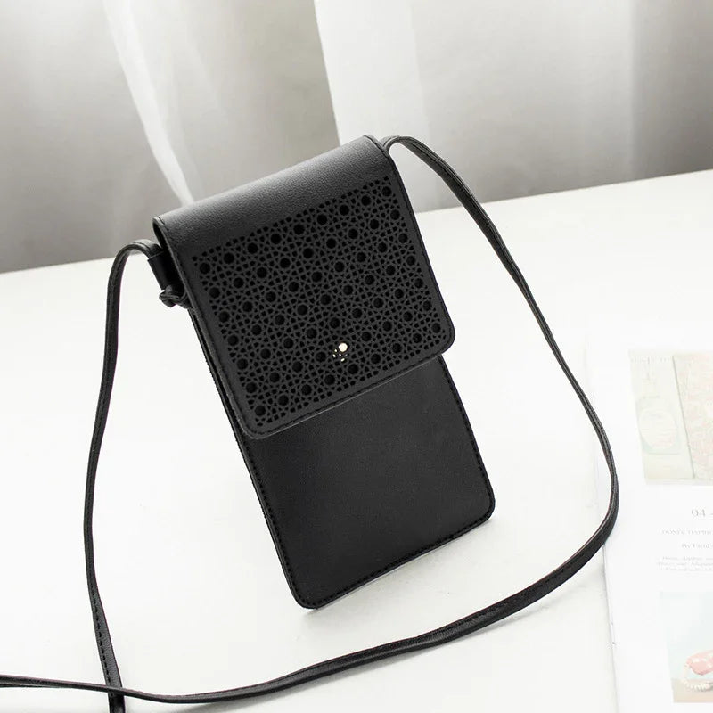 Black leather crossbody bag with intricate laser-cut floral design flap on white surface
