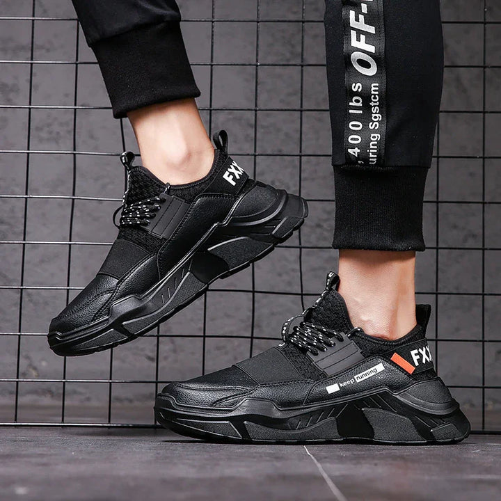 Black sporty casual sneakers with chunky soles and laces on person wearing black joggers