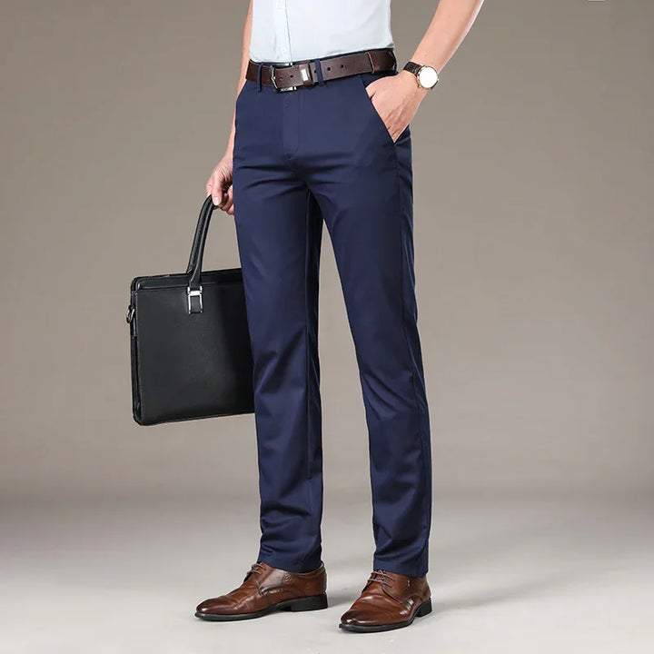 Man wearing navy blue formal trousers, brown leather belt and shoes, holding black briefcase