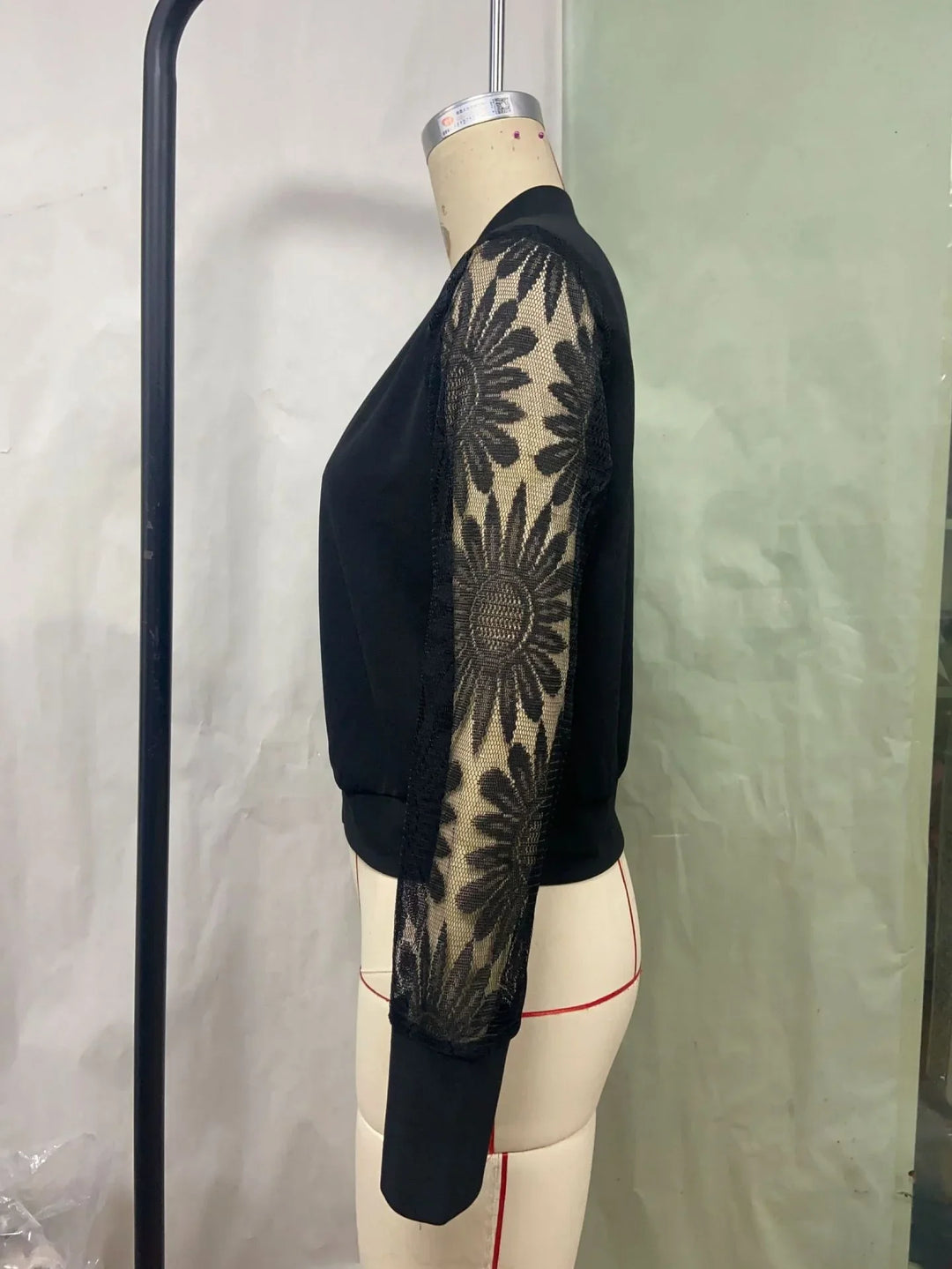 Black long-sleeve top with sheer floral lace sleeves on mannequin side view