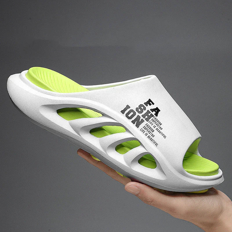 White and neon green foam slide sandal with text design, held in hand against gray background