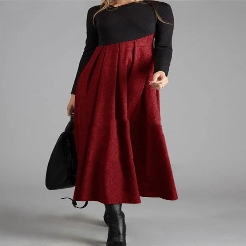 Woman wearing a long-sleeve black and red color block maxi dress with black boots and a black handbag