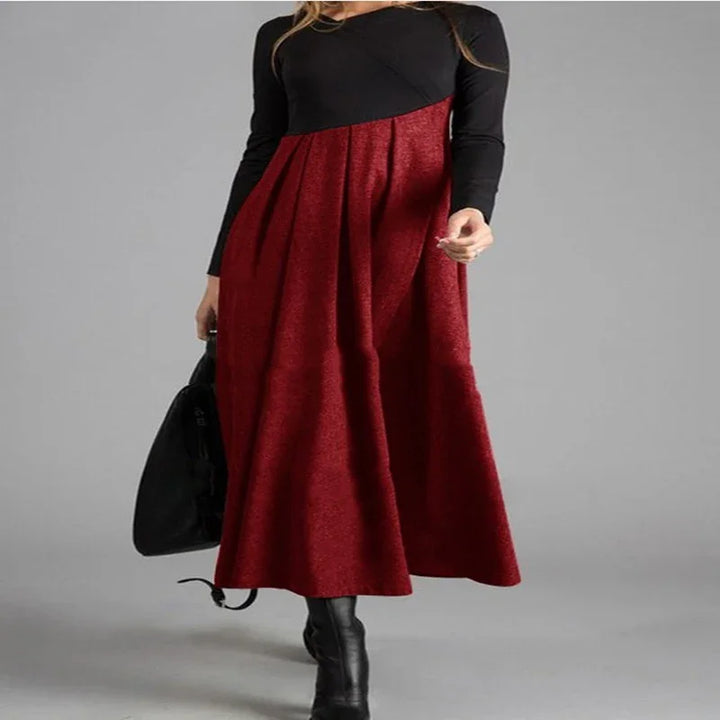 Woman wearing a long-sleeve black and red color block maxi dress with black boots and a black handbag