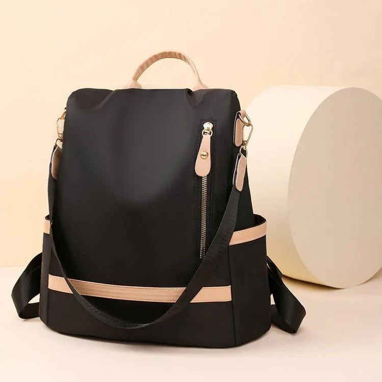 Black and beige nylon backpack with zipper pocket and adjustable shoulder straps on beige background