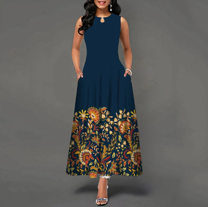 Woman wearing sleeveless navy blue maxi dress with colorful floral print at hem and pockets
