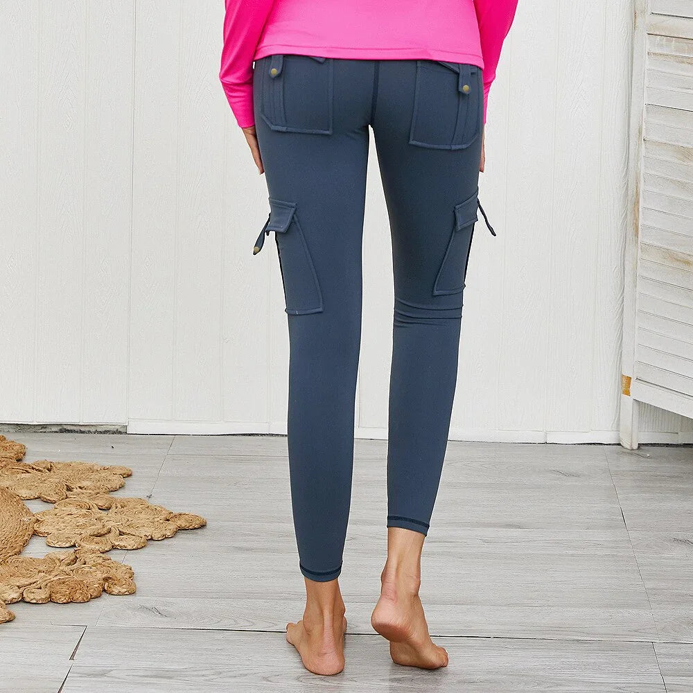 Rear view of person wearing dark blue cargo leggings with pockets, barefoot on wooden floor