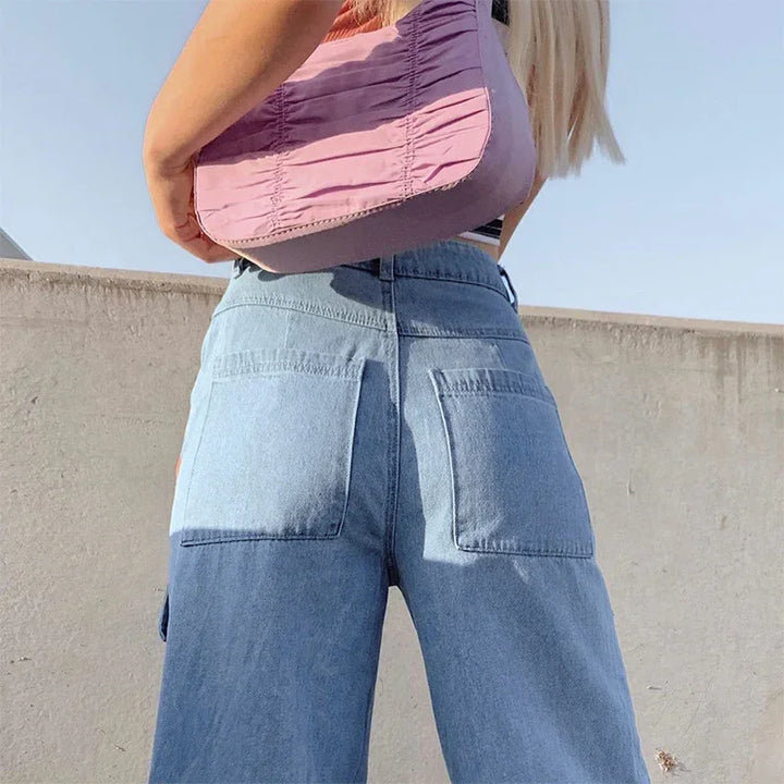 Back view of woman wearing two-tone blue denim jeans and carrying a pink ruched shoulder bag outdoors