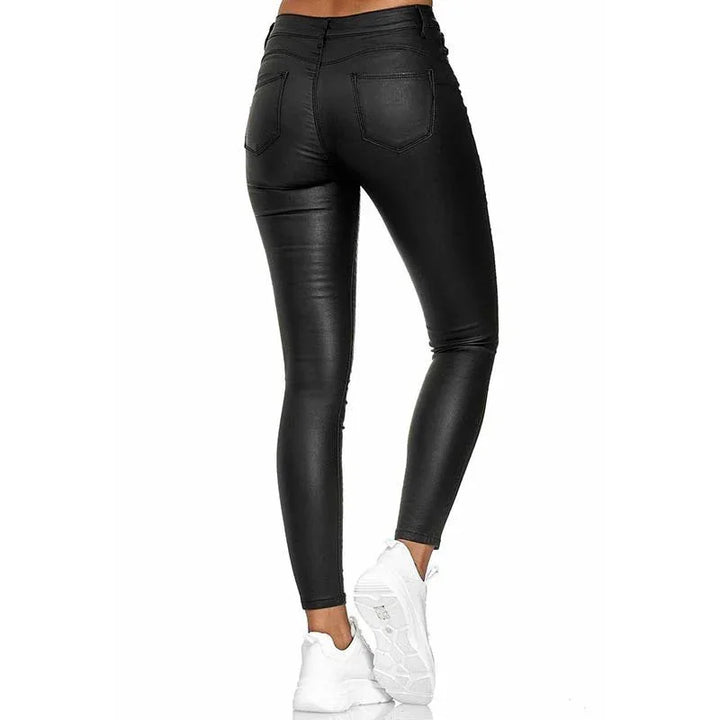 Back view of woman wearing black faux leather skinny pants paired with white sneakers on white background