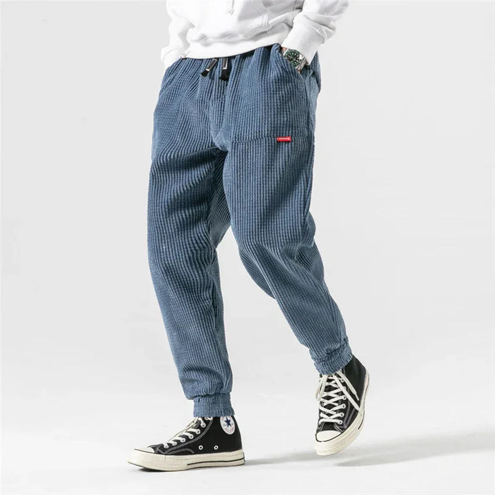 Modern blue corduroy jogger pants worn with black high-top sneakers and white hoodie