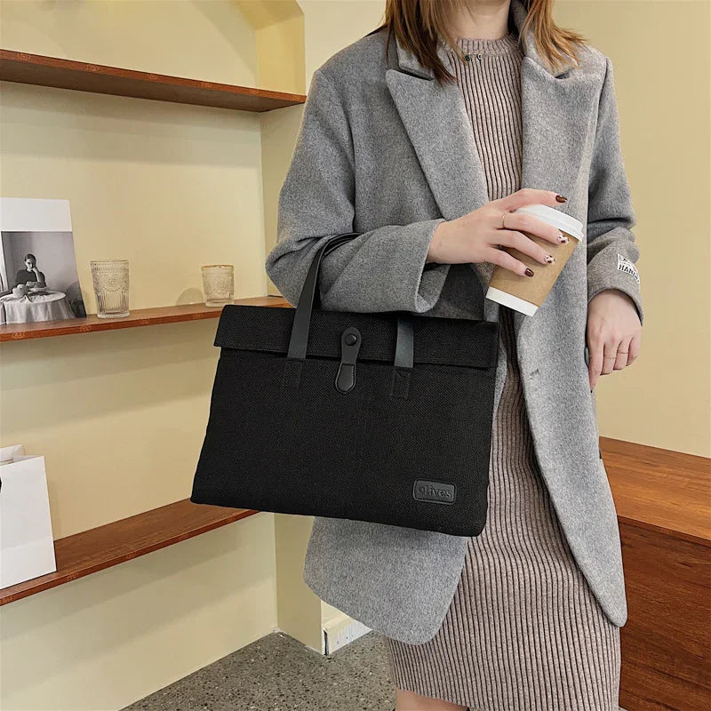 Woman in gray coat and ribbed dress holding black handbag and coffee cup indoors