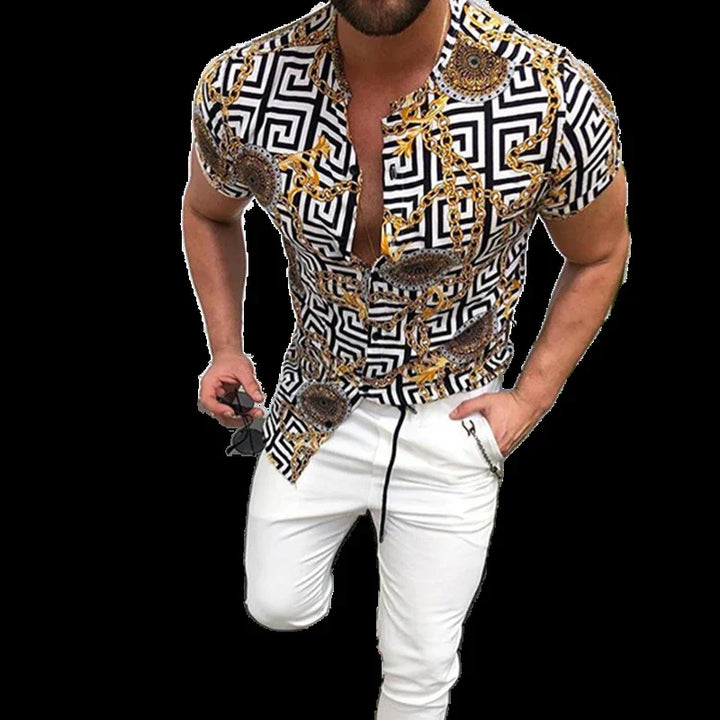 man wearing black and white geometric print shirt with gold chain patterns paired with white pants holding sunglasses